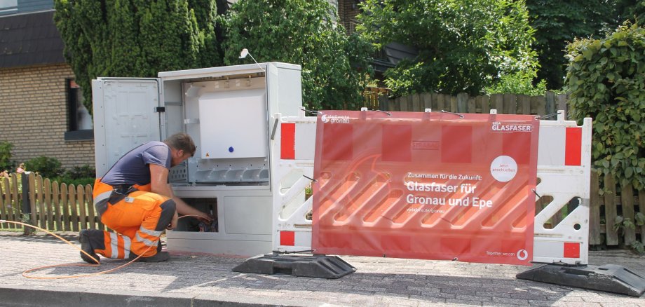 Eine Person arbeitet an einem Glasfaser-Auftrag in einer Straße.