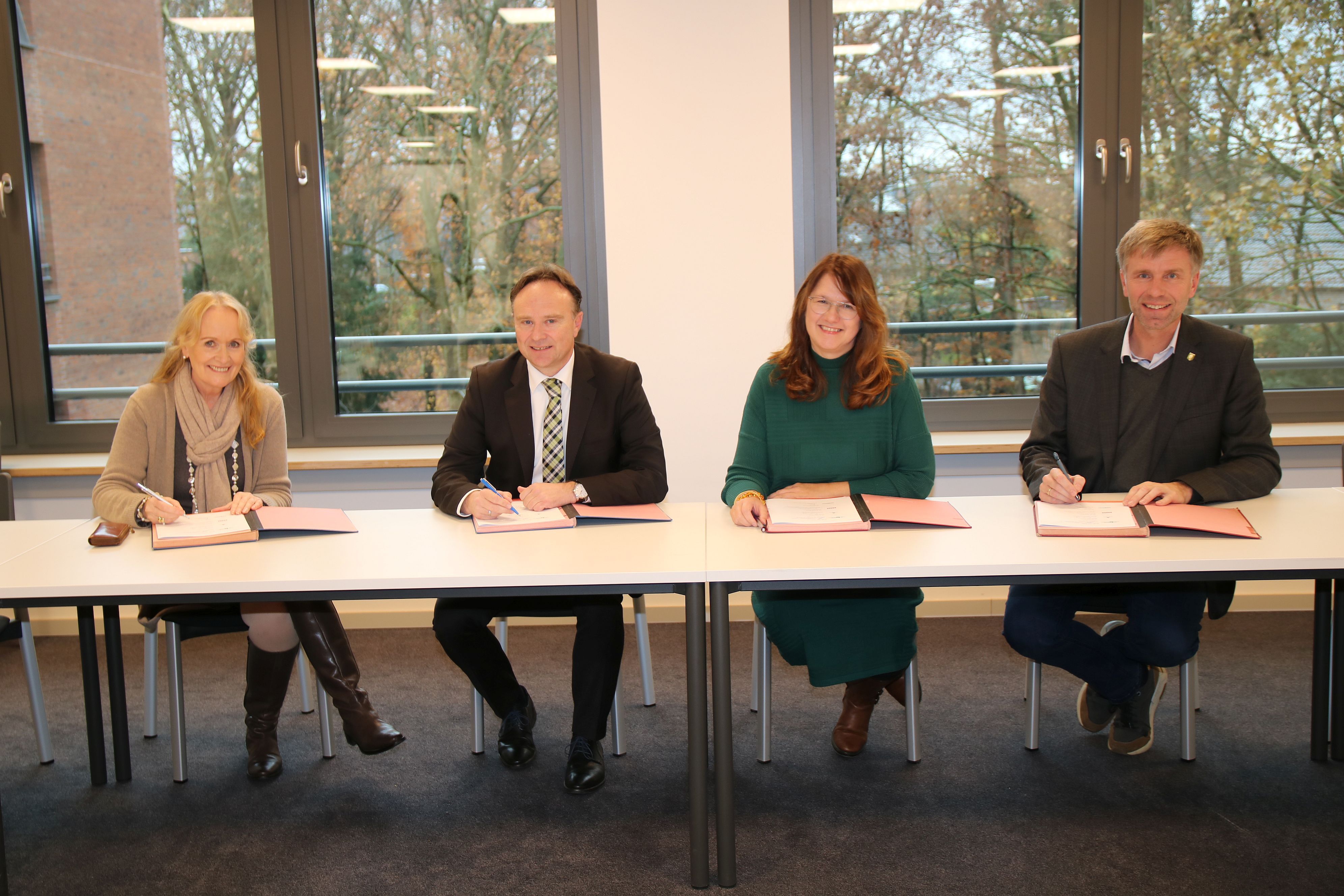 Bürgermeisterin Schulze Hessing, Landrat Dr. Zwicker, Bürgermeisterin Voß und Bürgermeister Doetkotte bei der Unterzeichnung an einem Tisch