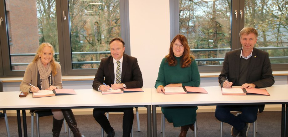Bürgermeisterin Schulze Hessing, Landrat Dr. Zwicker, Bürgermeisterin Voß und Bürgermeister Doetkotte bei der Unterzeichnung an einem Tisch