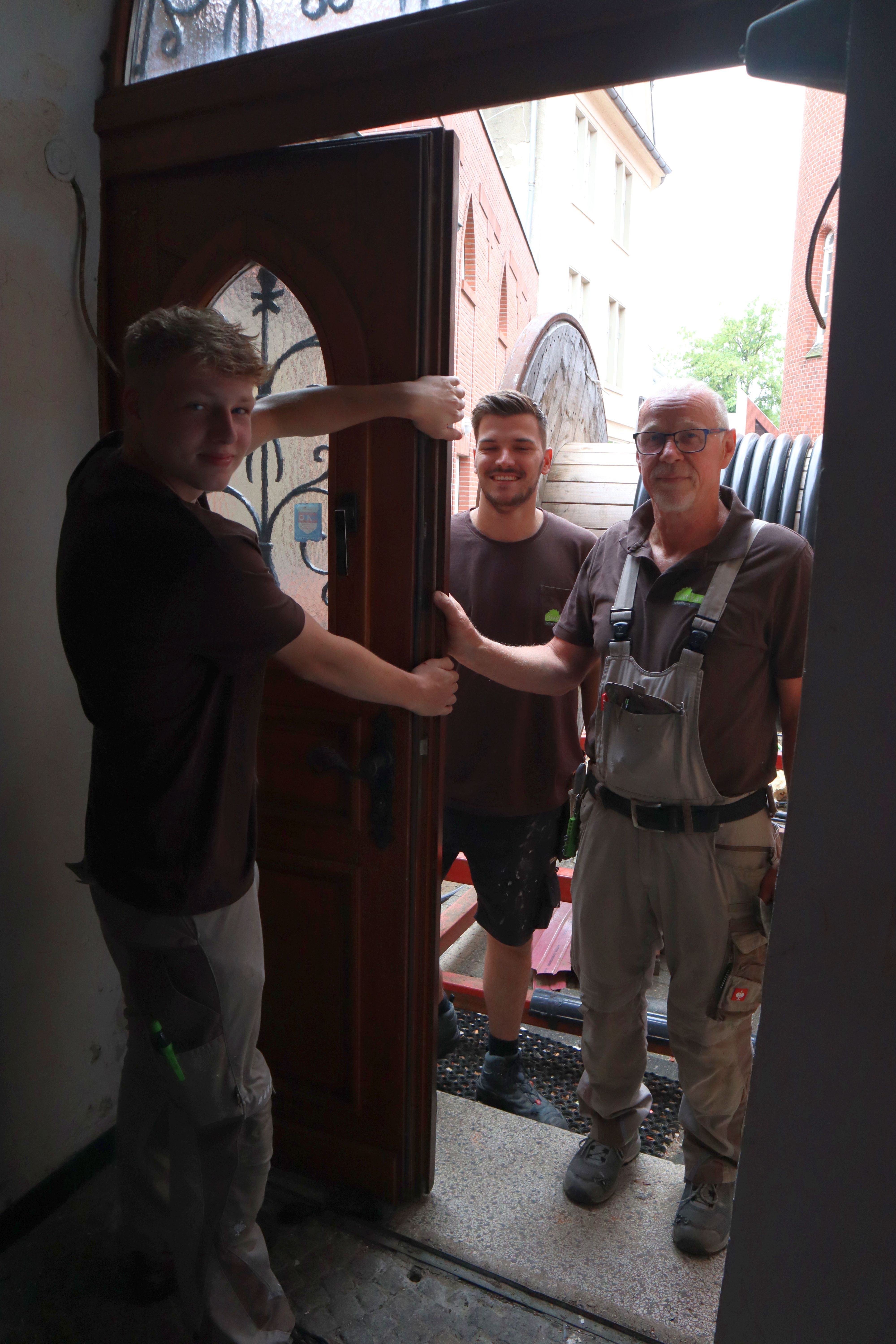 Eingangstür des ehemaligen Drilandmuseums mit Mitarbeitern der Fachfirma