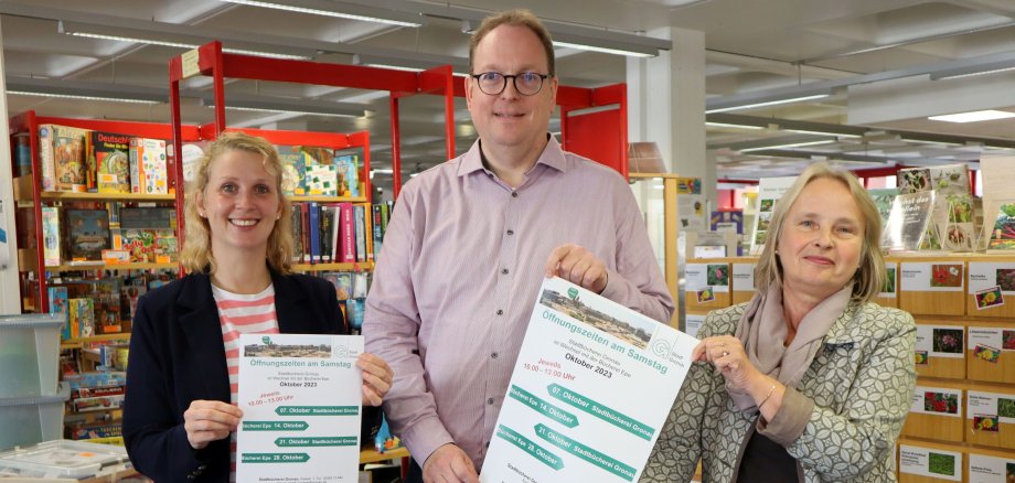 Anne Kammholz, Ulrich Lenzing und Helga Ausländer präsentieren ein Plakat mit den erweiterten Öffnungszeiten.