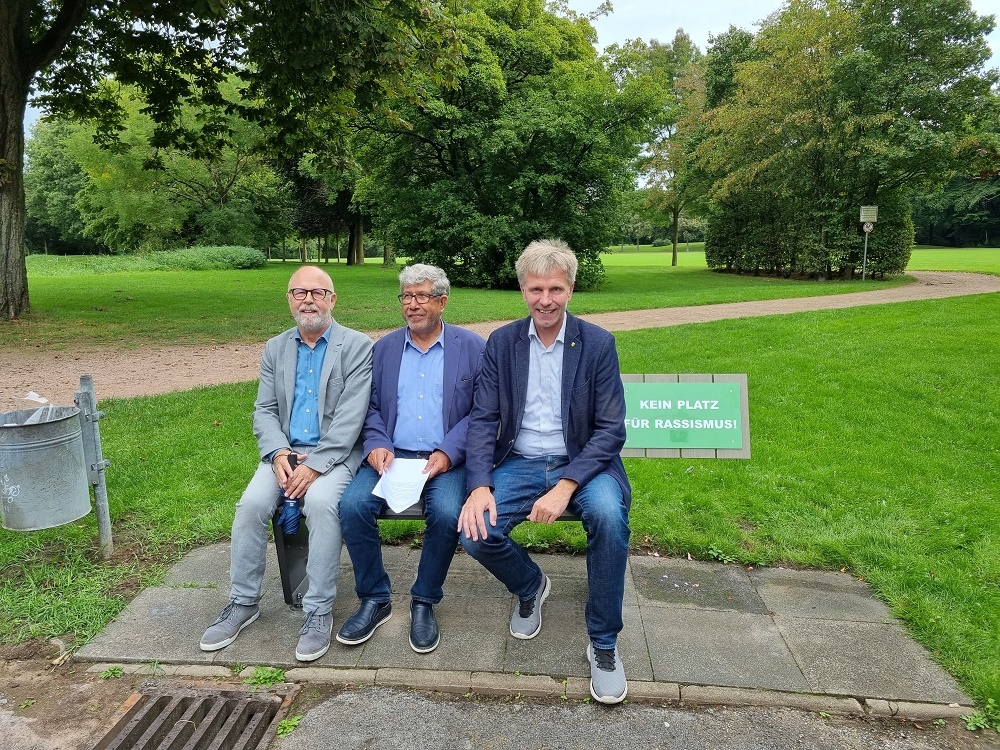 Eine neue Bank im Gronauer Stadtpark kein Platz für Rassismus. Auf der Bank von links nach rechts sitzen Herr Lüttmann, Herr Sezer und Herr Doetkotte.
