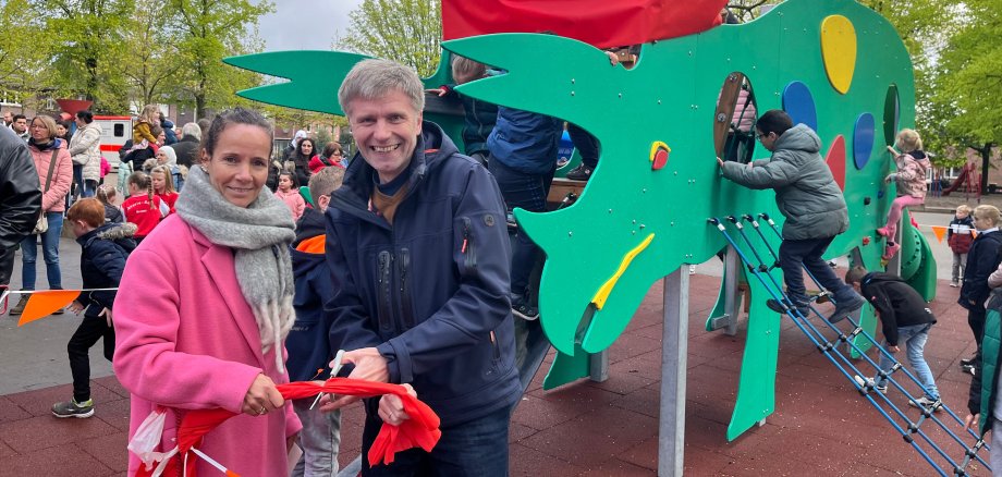 Schulleiterin Maike Albers-Wilmes und Bürgermeister Rainer Doetkotte durchtrennen das traditionelle Eröffnungsband des neuen Dino-Klettergerüstes.