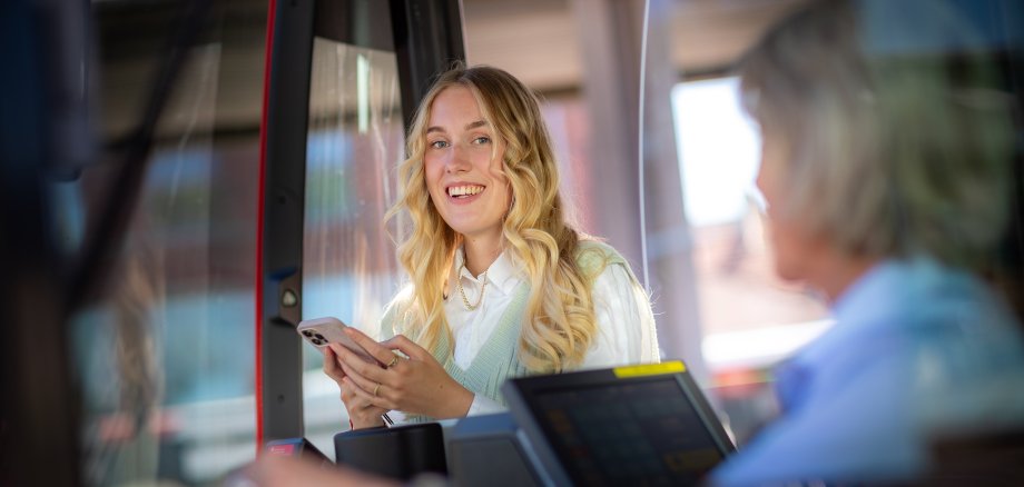 Ein junge Frau nimmt am Handy an der Online-Umfrage zur Bus&Bahn im Münsterland-App (BuBiM-App) teil.