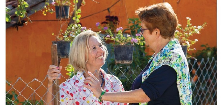 Zwei Nachbarinnen reichen sich die Hände