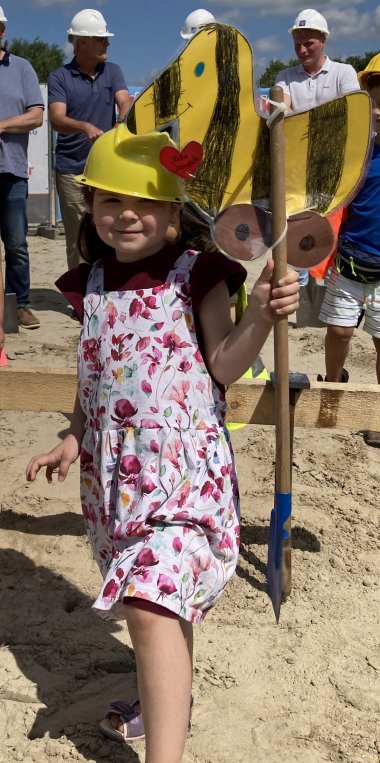 Kind mit Bauhelm und einem Spaten