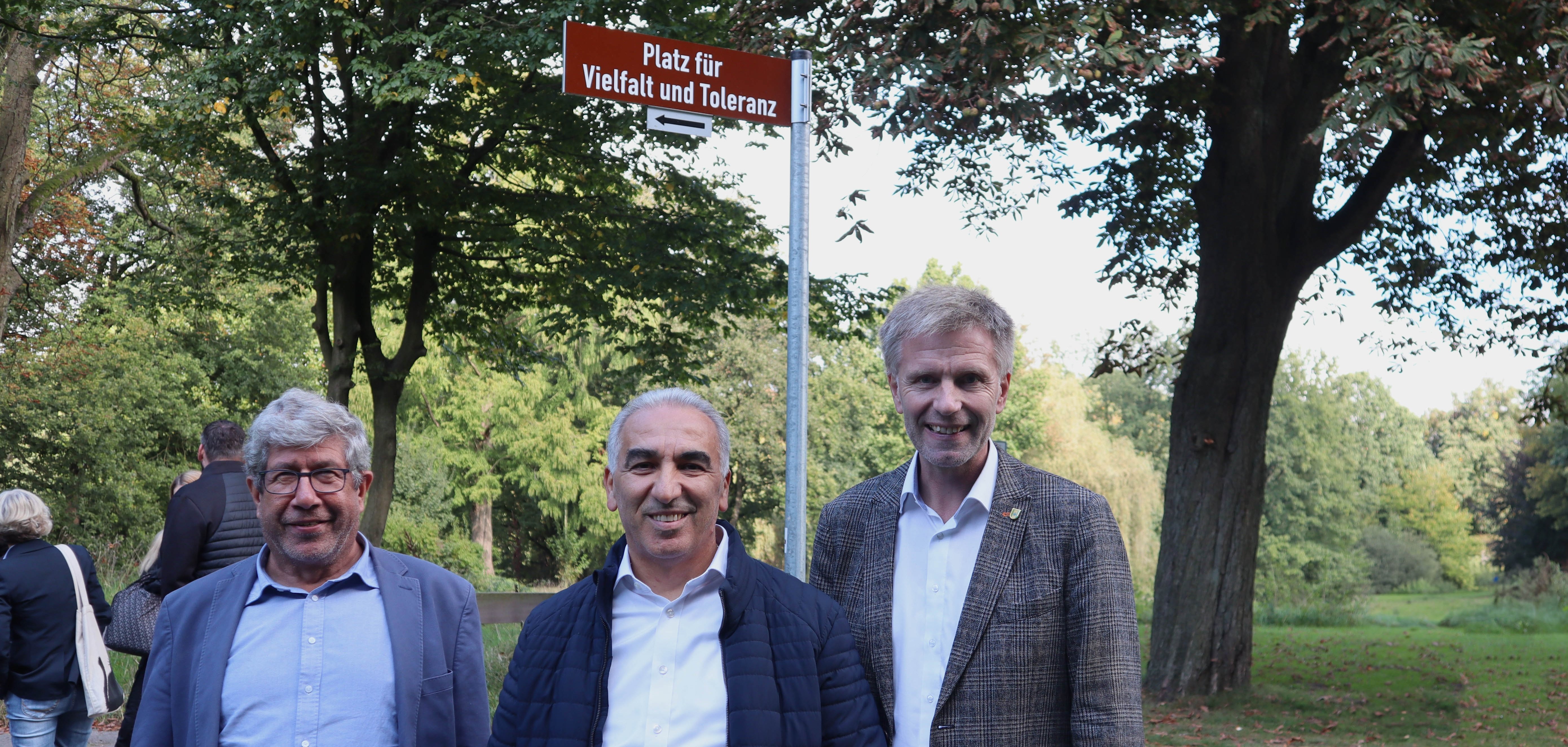 Integrationsbeauftragter Ahmet Sezer, Vorsitzende des Integrationsrates Ibrahim Savci und Bürgermeister Rainer Doetkotte vor dem neuen Schild "Platz für Vielfalt und Toleranz"