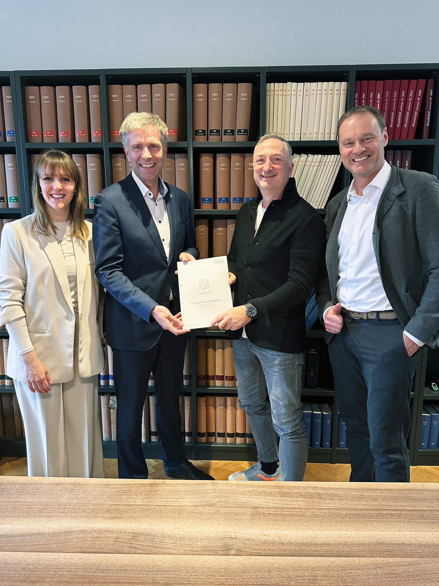 Katharina Vater, Bürgermeister Rainer Doetkotte und zwei Vertreter der Firma Bakerman zeigen einen Vertrag