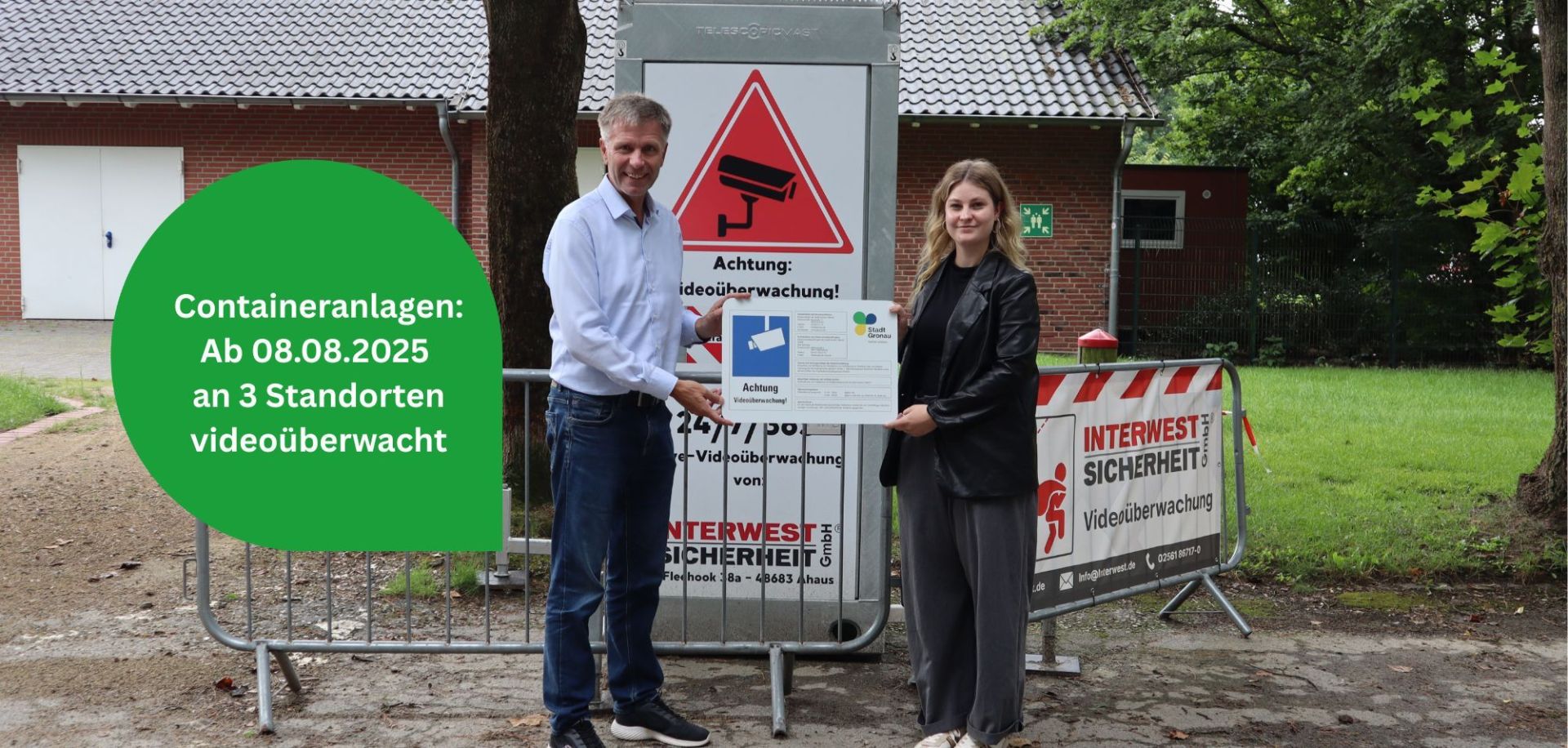 Bürgermeister Rainer Doetkotte und Verwaltungsmitarbeiterin Christin Meyer halten ein Schild mit Informationen zur Videoüberwachung