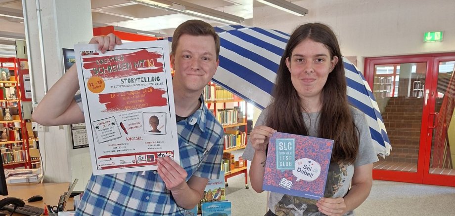 Marvin Dolansky und Leonie Schmolke von der Stadtbücherei Gronau zeigen die Plakate zum SommerLeseClub