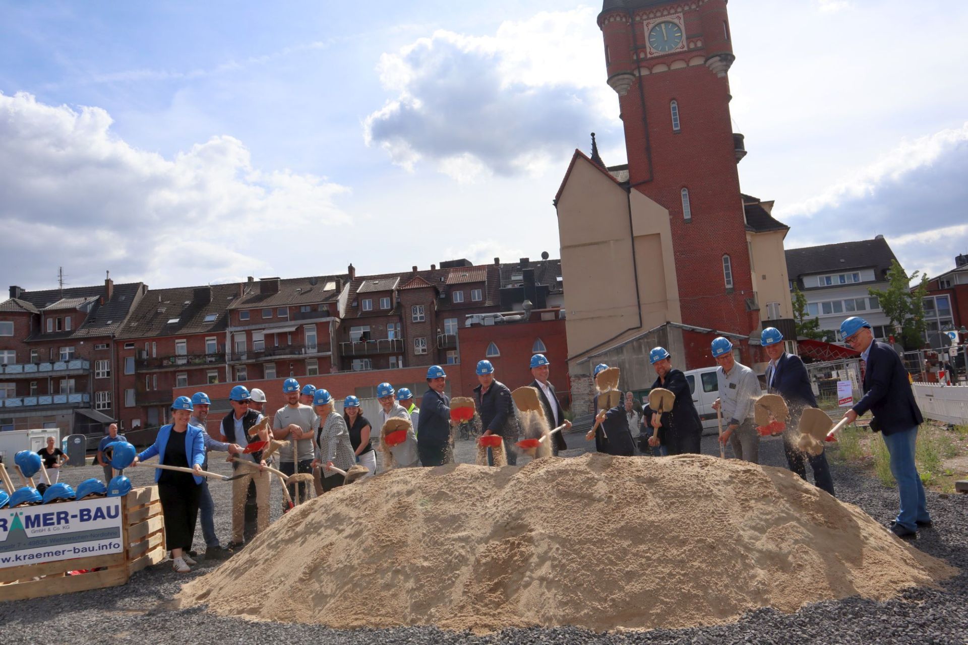 Gruppe von Menschen mit Bauhelmen und Spaten auf der Baustelle an der Bahnhofstraße 
