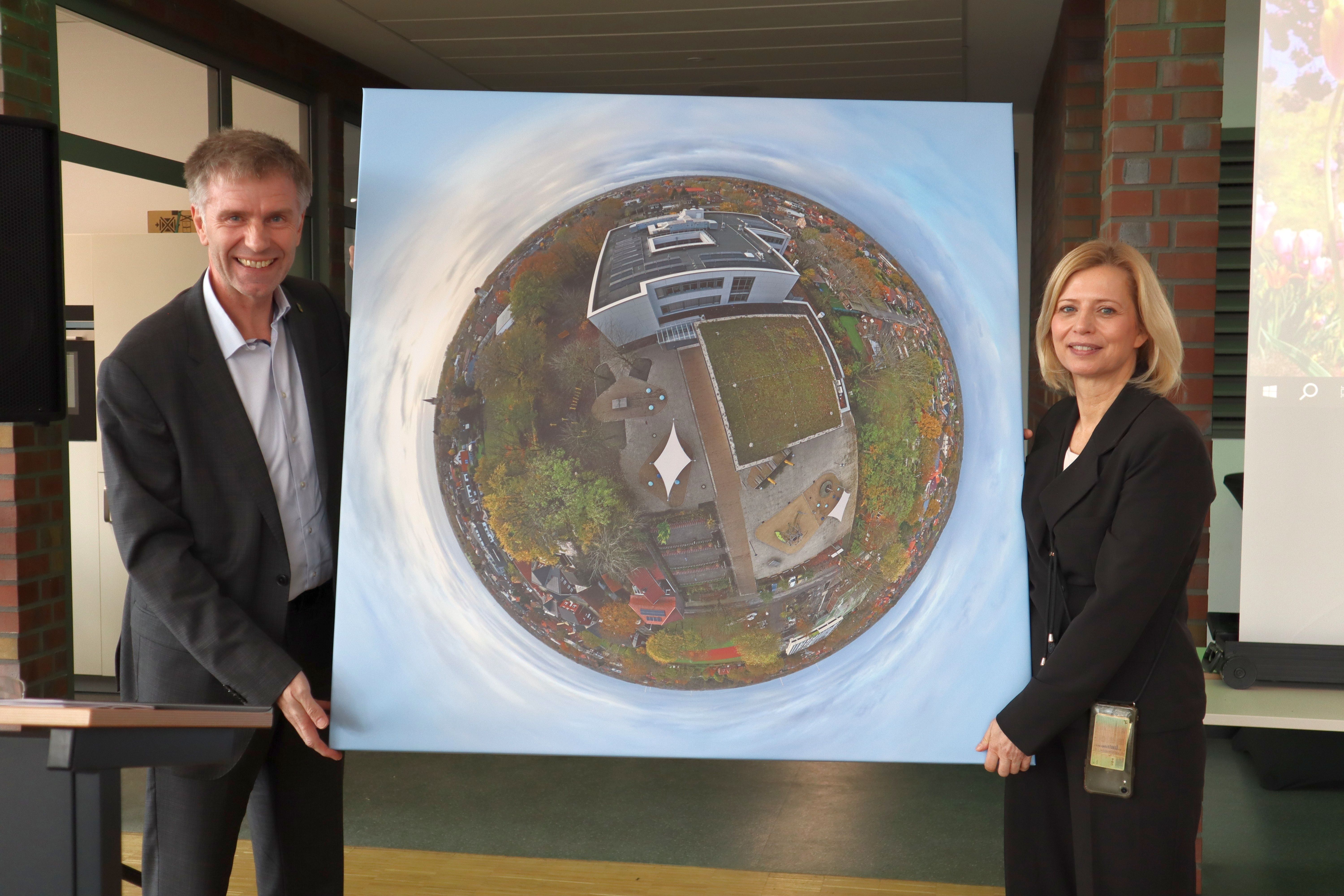 Bürgermeister Rainer Doetkotte und Schulleiterin Dagmar Dengler mit einem Luftbild der Schule