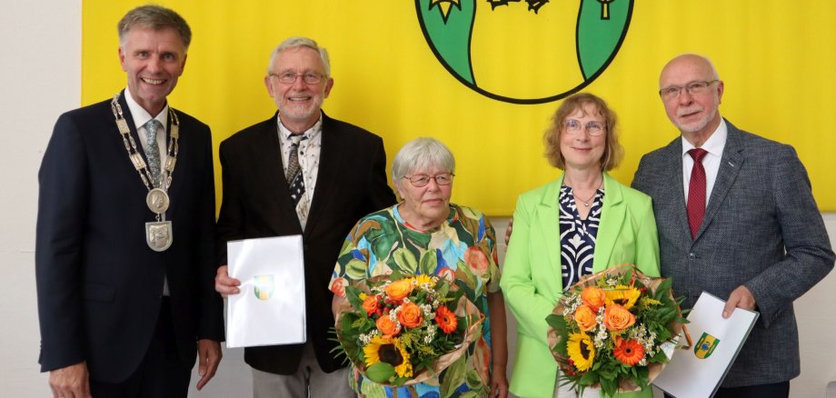 Bürgermeister Rainer Doetkotte mit den Geehrten Georg Gartmann und Franz Josef Terlinde und den Ehepartnern im Ratssaal vor der Gronauer Fahne