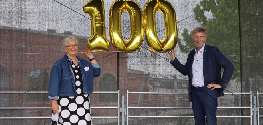 Erste Beigeordnete Christiane Schrader und Bürgermeister Rainer Doetkotte mit einer goldenen "100" auf einer Bühne