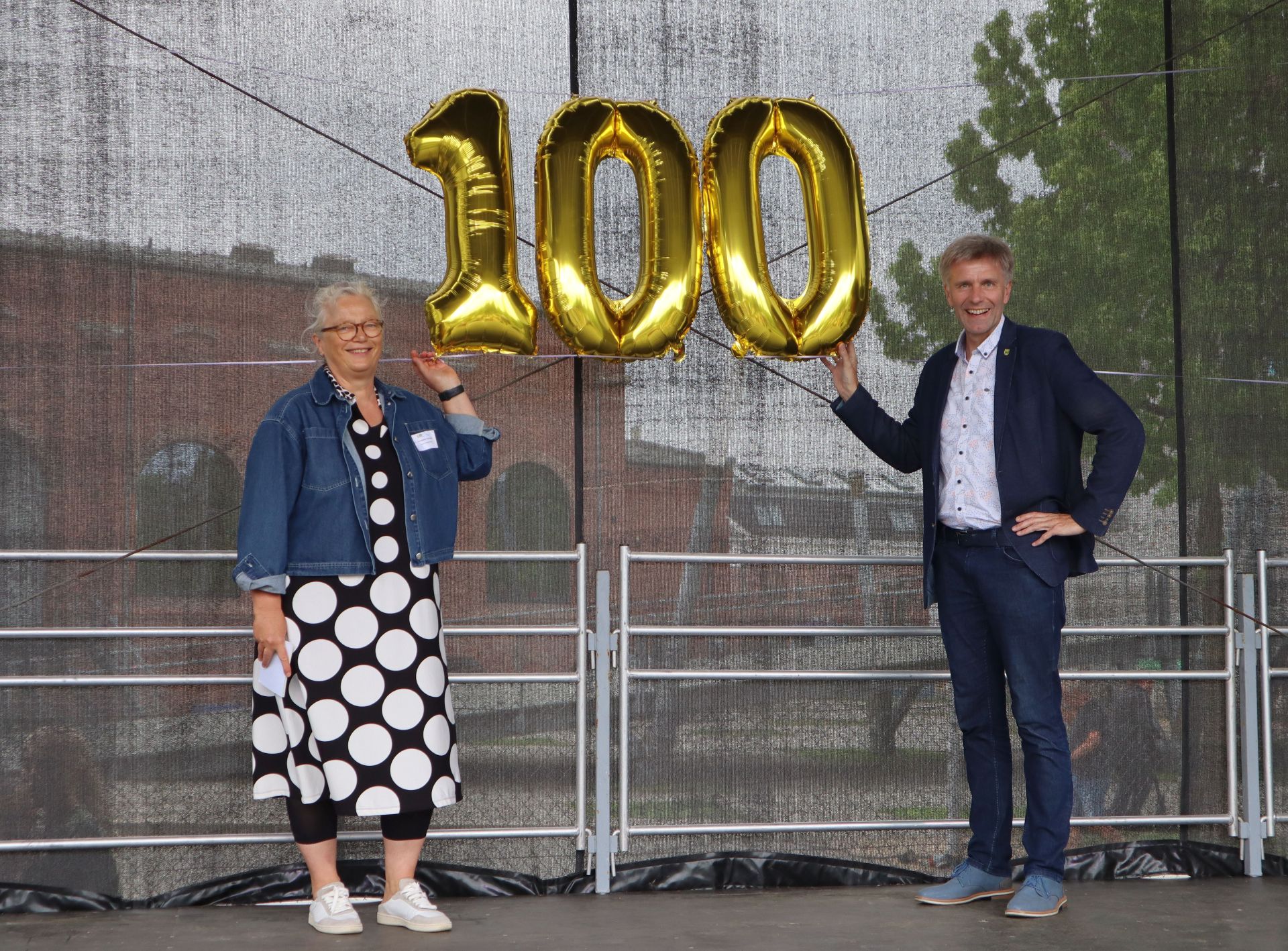 Erste Beigeordnete Christiane Schrader und Bürgermeister Rainer Doetkotte mit einer goldenen "100" auf einer Bühne