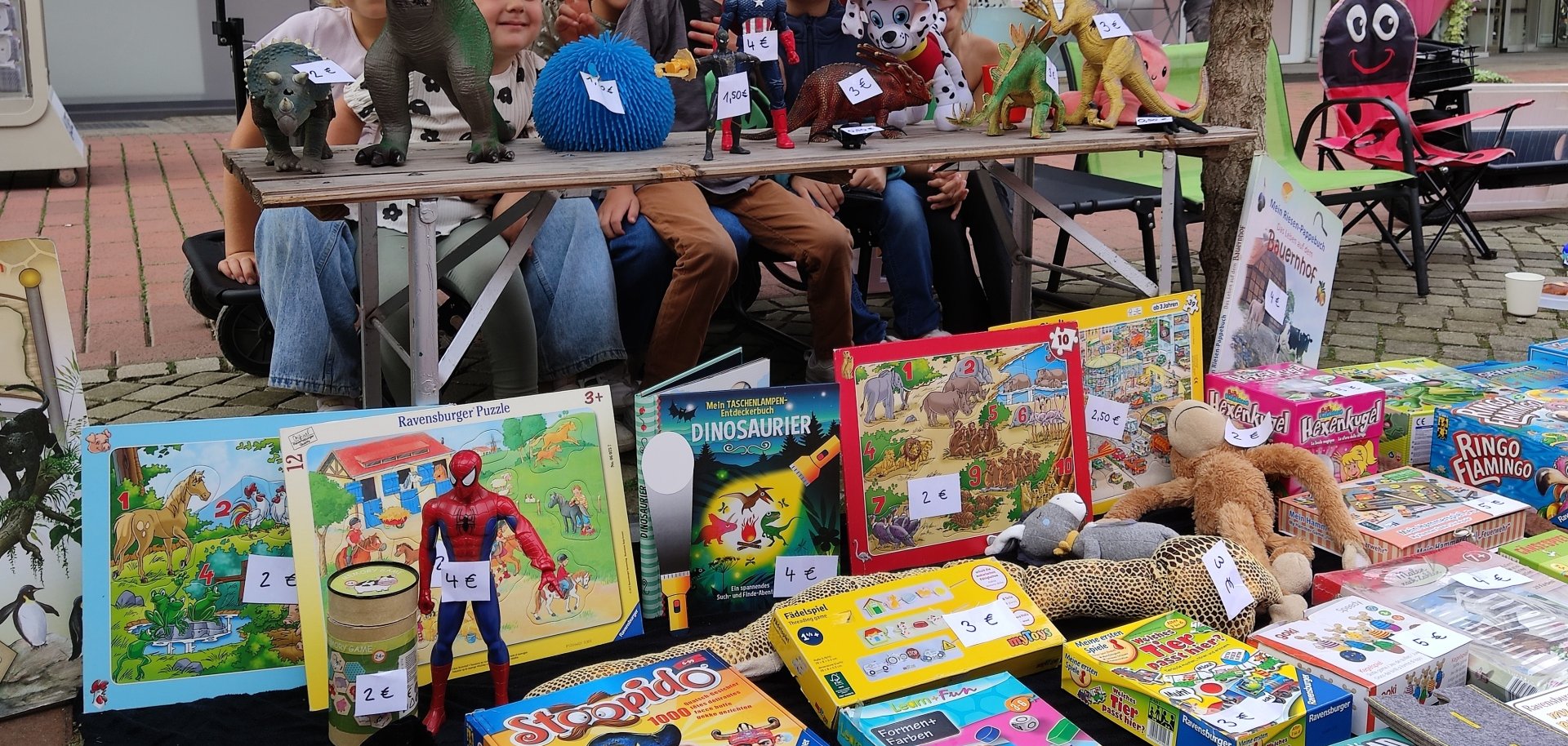 Kinder verkaufen an ihrem Stand Spielzeuge und Bücher.