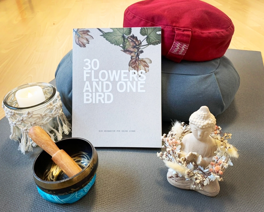 Das Buch "30 flowers and one bird" von Linda Wagner angelehnt an einem Yogakissen.