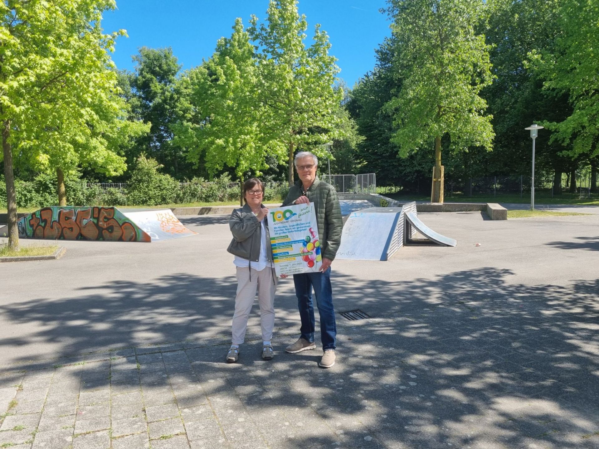Brigitte Amshoff und Rainer Hülskötter präsentieren das Werbeplakat zum Jubiläum "100 Jahre Jugendamt Gronau".