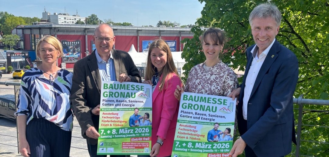 Die Veranstalter:innen, die Wirtschaftsförderung und der Bürgermeister präsentieren die Plakate zur Baumesse.