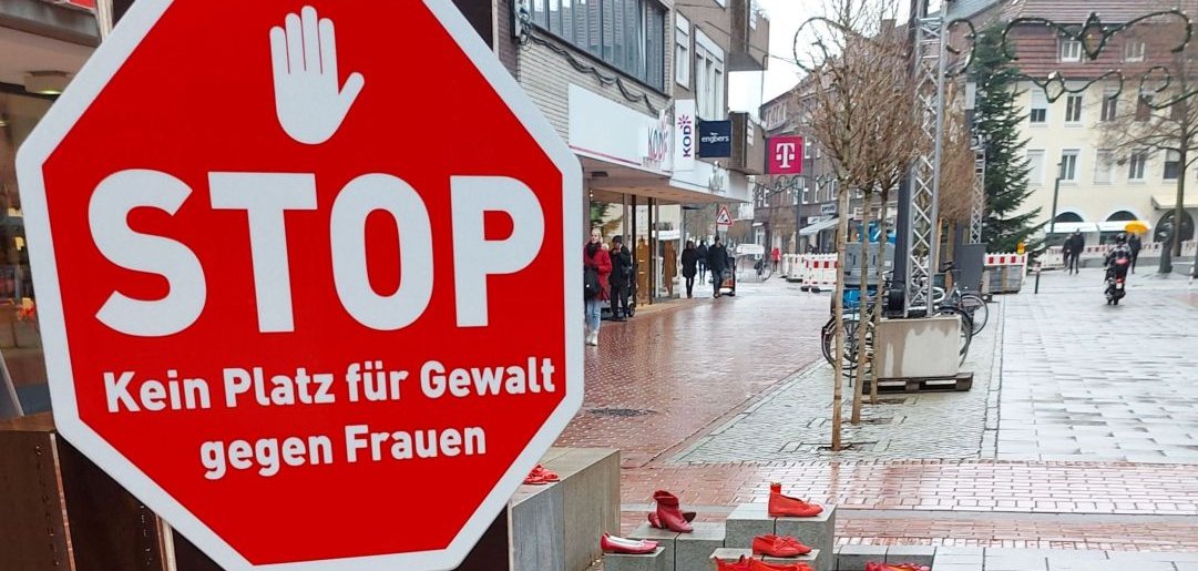 Rote Schuhinstallation neben einem Stoppschild mit der Aufschrift ‚Kein Platz für Gewalt gegen Frauen‘