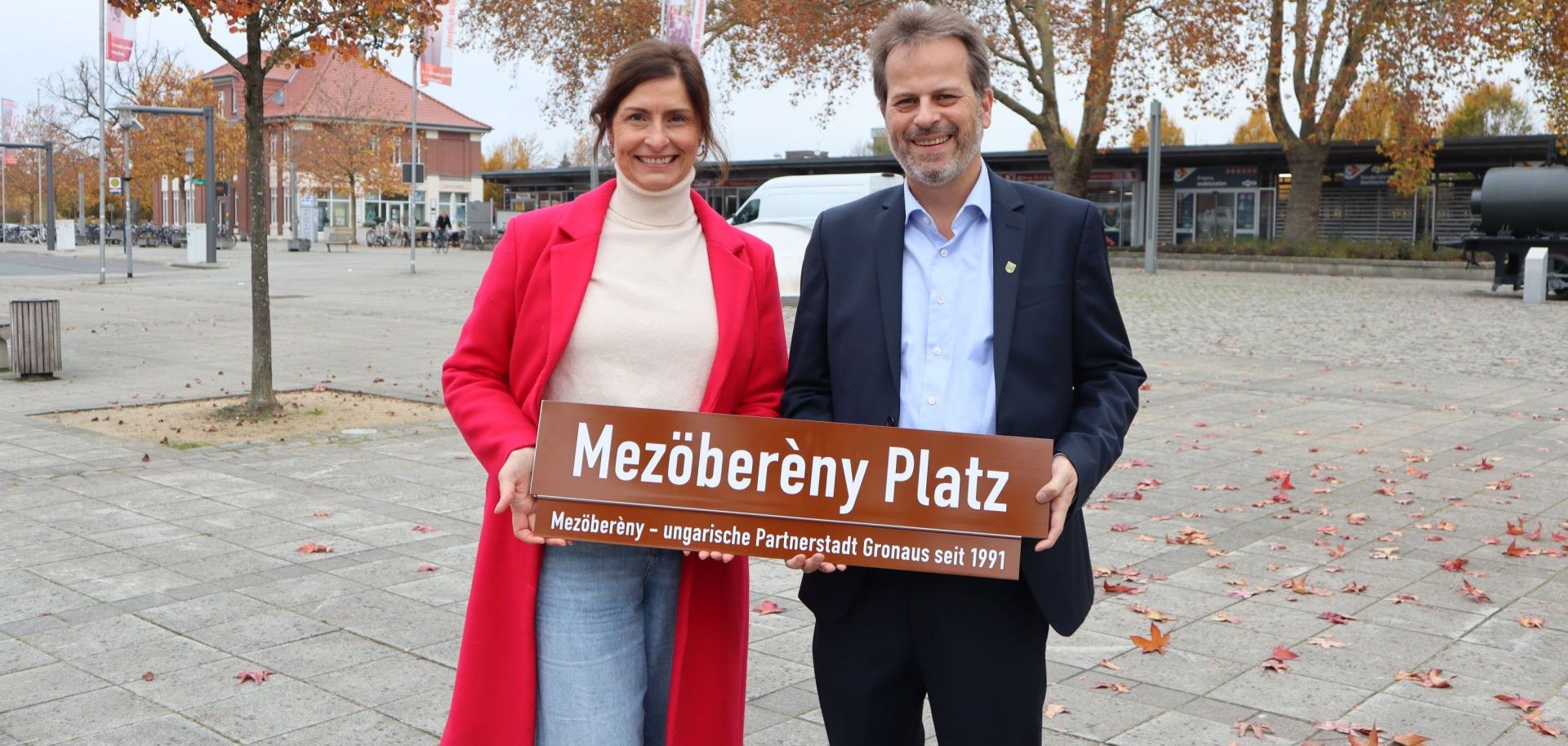 Marta Lohle-Mórocz und Bürgermeister Jörg von Borczyskowski präsentieren das neue Schild für den Platz am Bahnhof