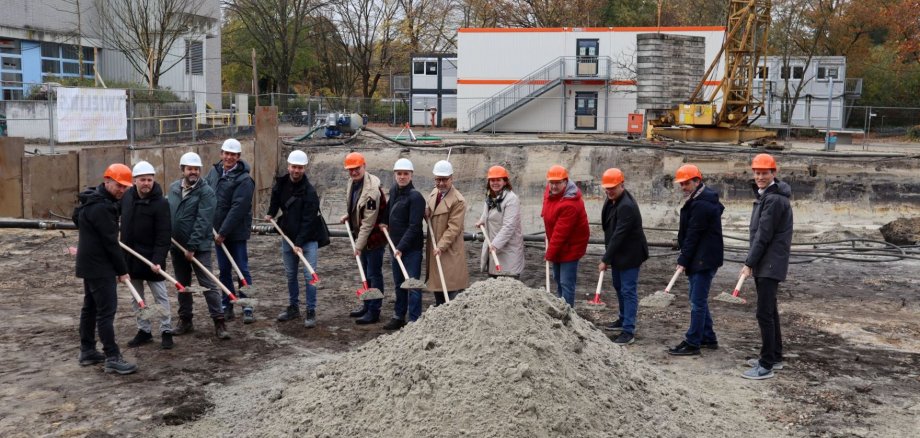 Gruppe von Menschen mit Bauhelmen und Spaten auf der Baustelle zur Erweiterung am Werner-von-Siemens-Gymnasium Gruppe von Menschen mit Bauhelmen und Spaten auf der Baustelle zur Erweiterung am Werner-von-Siemens-Gymnasium