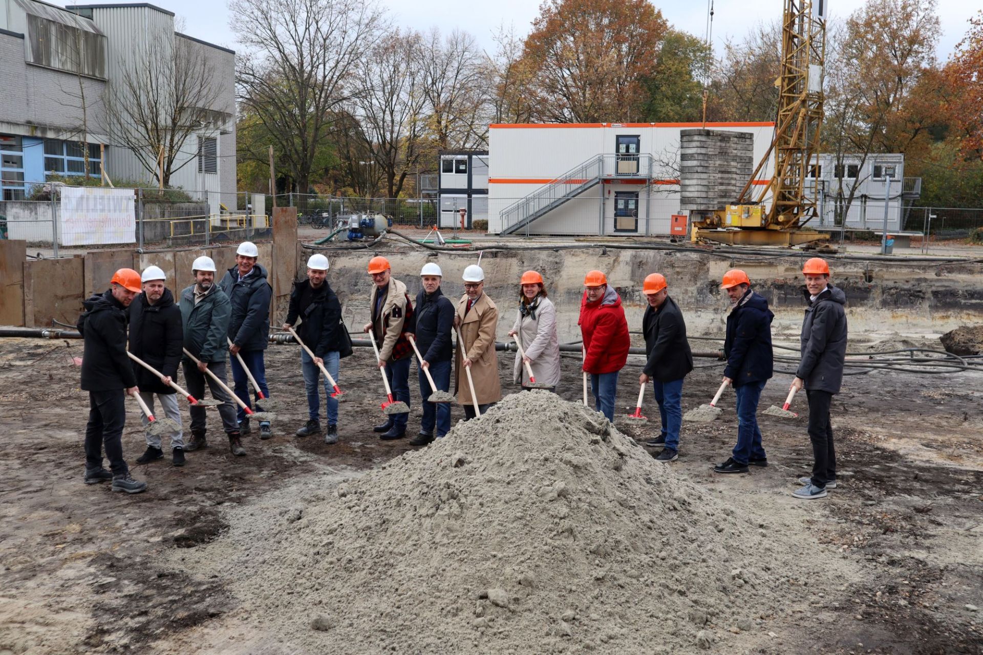 Gruppe von Menschen mit Bauhelmen und Spaten auf der Baustelle zur Erweiterung am Werner-von-Siemens-Gymnasium