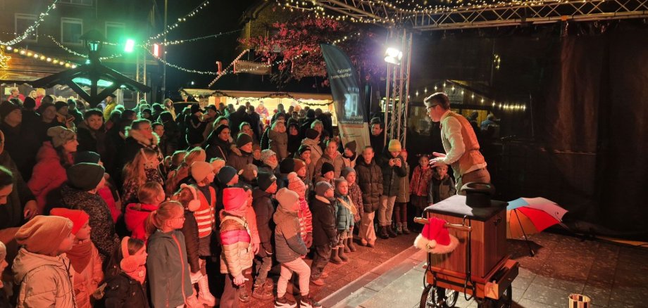 Auf der Bühne des Eper Weihnachtsmarkts tritt eine Person auf und begeistert viele gespannt zuschauende Kinder und Erwachsene Auf der Bühne des Eper Weihnachtsmarkts tritt eine Person auf und begeistert viele gespannt zuschauende Kinder und Erwachsene