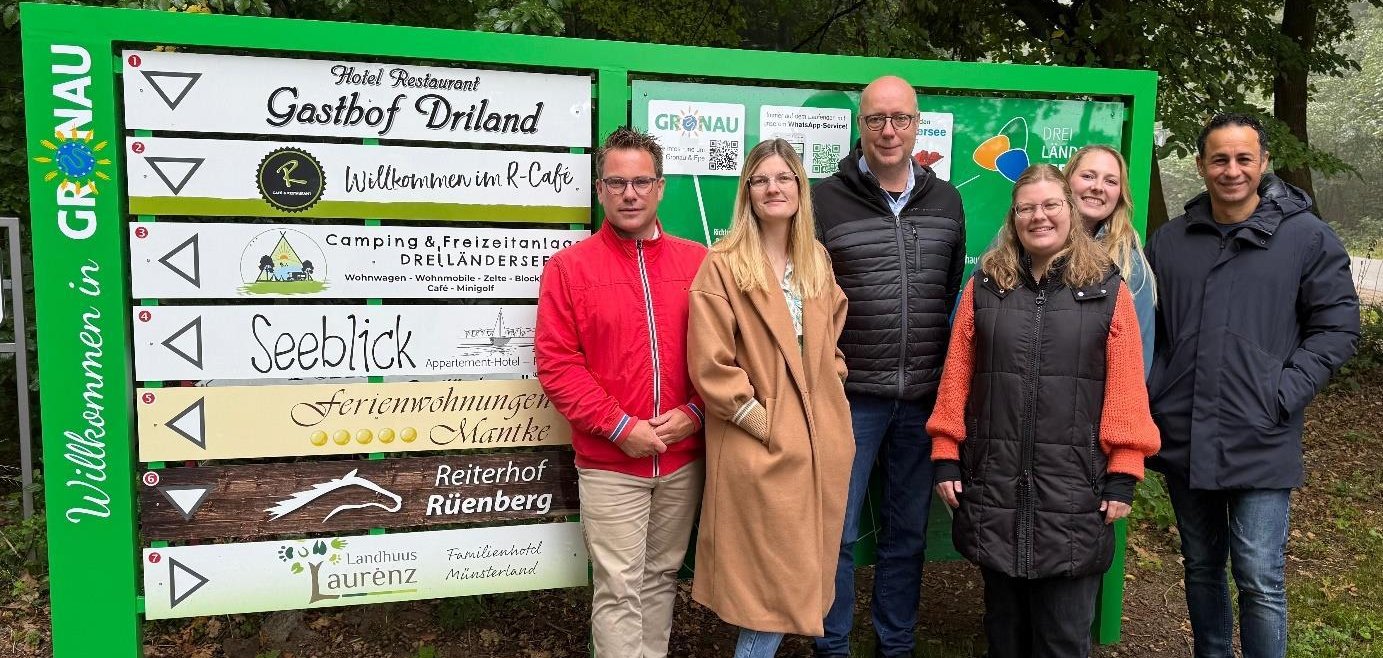 Sebastian Stern (Stadt Gronau), Lorena Schwägerl (Appartementhotel Restaurant Seeblick), Thomas Berning (Gasthof Driland), Anne Holters (Stadtmarketing Gronau), Nina Röwekamp (Camping- & Freizeitanlage Dreiländersee) und Ali Sanli (R-Café Gronau) weihen gemeinsam die neue Beschilderung am Dreiländersee ein. Vertreter:innen der Ferienwohnungen Mantke, des Landhuus Laurenz sowie des Reiterhofs Rüenberg fehlen auf diesem Bild.