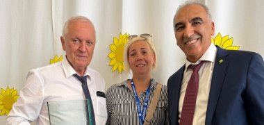Ibrahim Savci, 1. stellvertretender Bürgermeister der Stadt Gronau, und Bürgermeister István Siklósi aus Mezőberény gemeinsam mit der Dolmetscherin nach der Übergabe der gravierten Glasplakette als Gastgeschenk der Stadt Gronau.