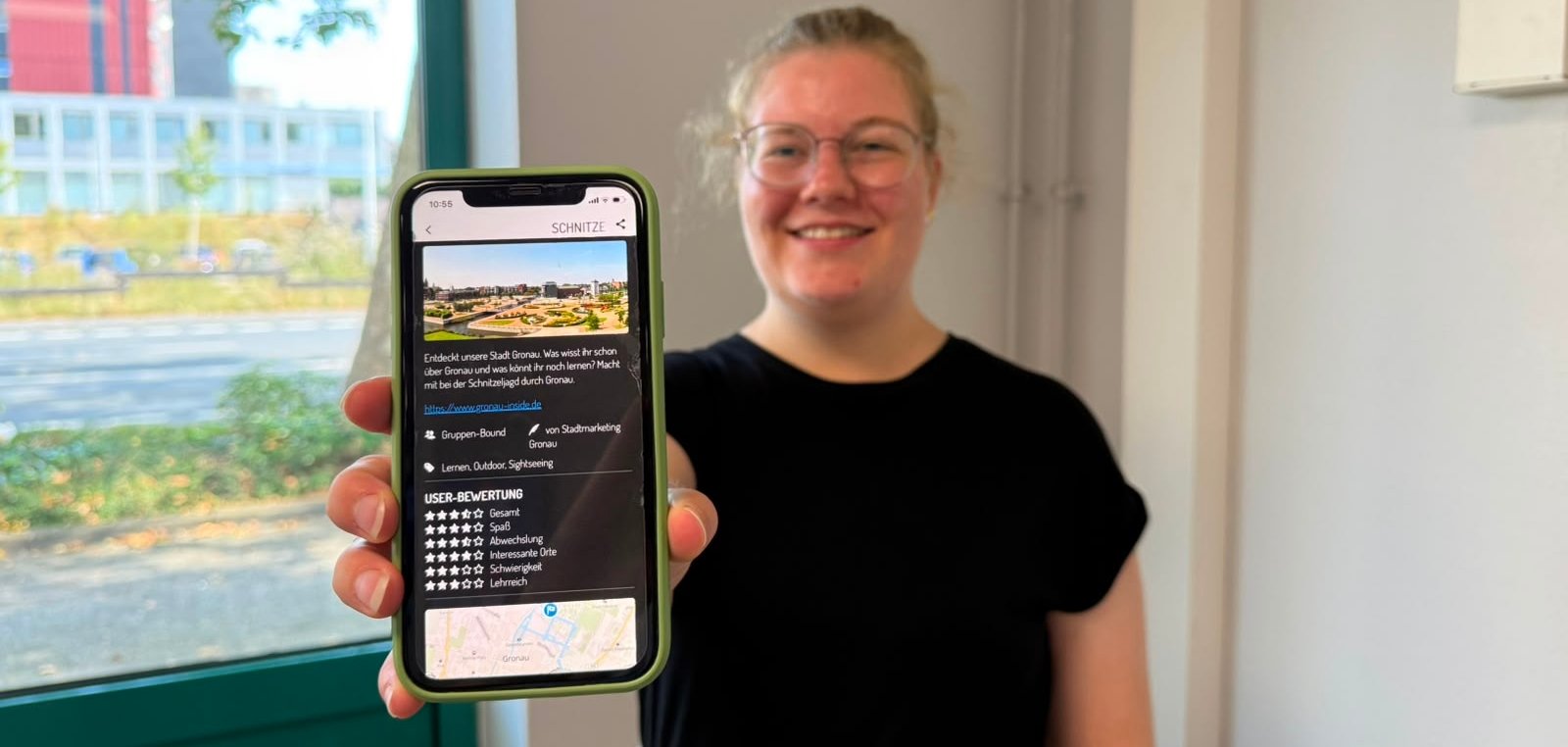 Eine Person hält ein Smartphone zur Kamera auf der die App Actionbound geöffnet ist.