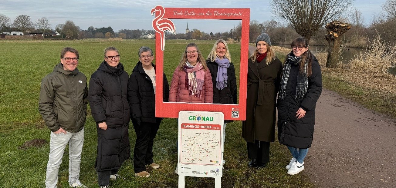 Vertreter der beteiligten Kommunen und des Kreises Borken weihen die Flamingo-Fotorahmen ein. V.l.n.r.: Martin Auras (SMS – StadtMarketing Stadtlohn e. V.), Lena Kerkeling (Stadtmarketing Gronau), Doris Büning (Gemeinde Schöppingen), Anne Holters (Stadtmarketing Gronau), Julia Gesing (Kreis Borken), Karina Wozniak-Arends (Stadtmarketing Vreden) und Antonia Weiper (Gemeinde Heek). Es fehlen Vertreter der Kommunen Gescher, Ahaus und Legden.