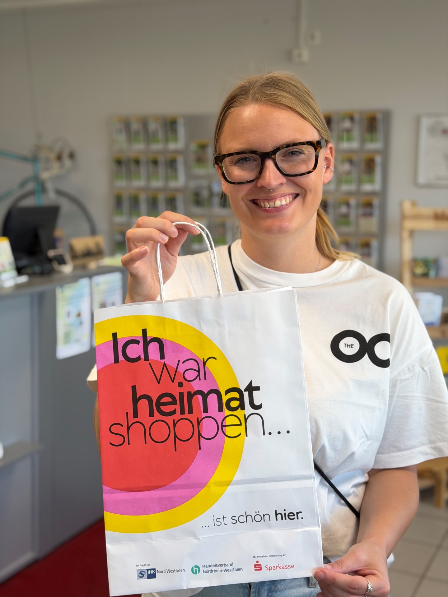Lena Kerkeling aus dem Stadtmarketing zeigt eine Papiertüte mit der Aufschrift "Ich war heimat shoppen... ist schön hier." 