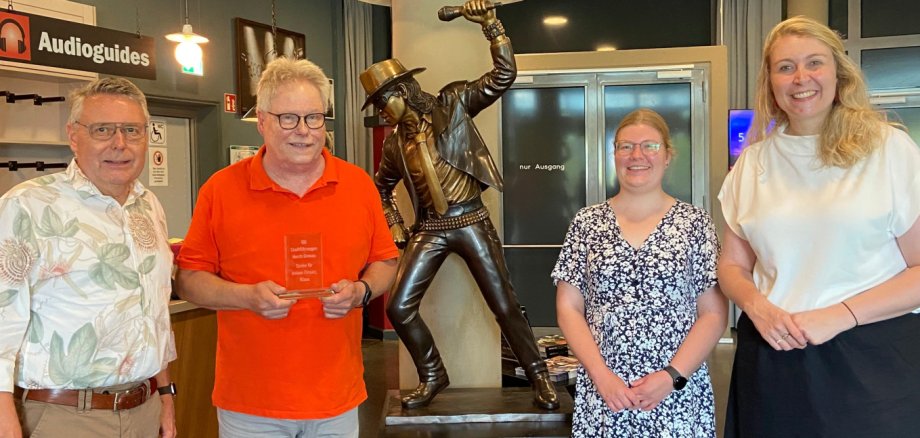 Thomas Albers, Katharina Terhan und Anne Holters überreichen Klaus Wiedau eine kleine Aufmerksamkeit für 100 Stadtführungen durch Gronau. 