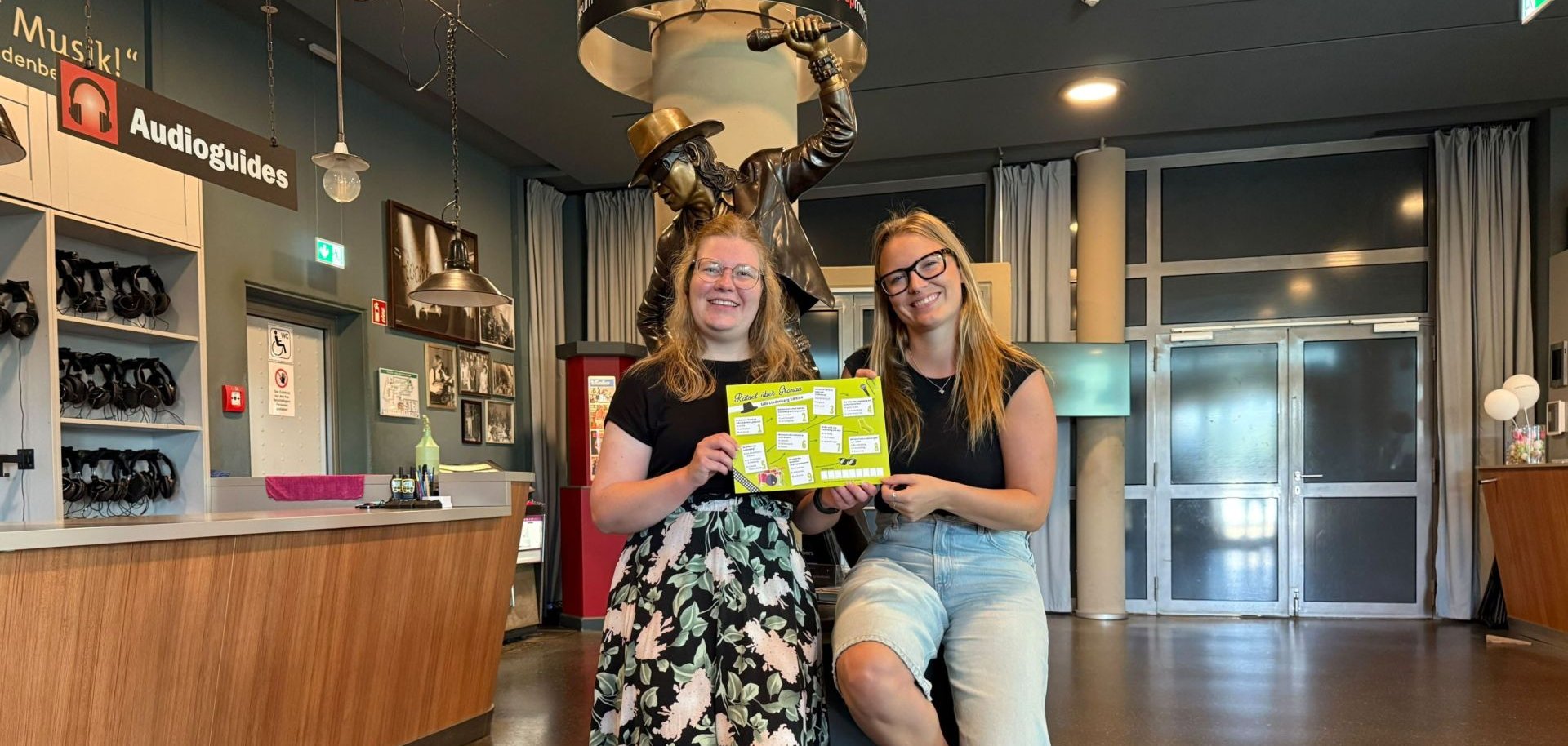 Anne Holters und Lena Kerkeling aus dem Stadt- und Tourismusmarketing stehen im rock'n'pop Museum vor einer Udo Lindenberg Figur.