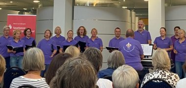 Ein Chor singt vor Publikum in der Sparkasse Ein Chor singt vor Publikum auf einer Bühne