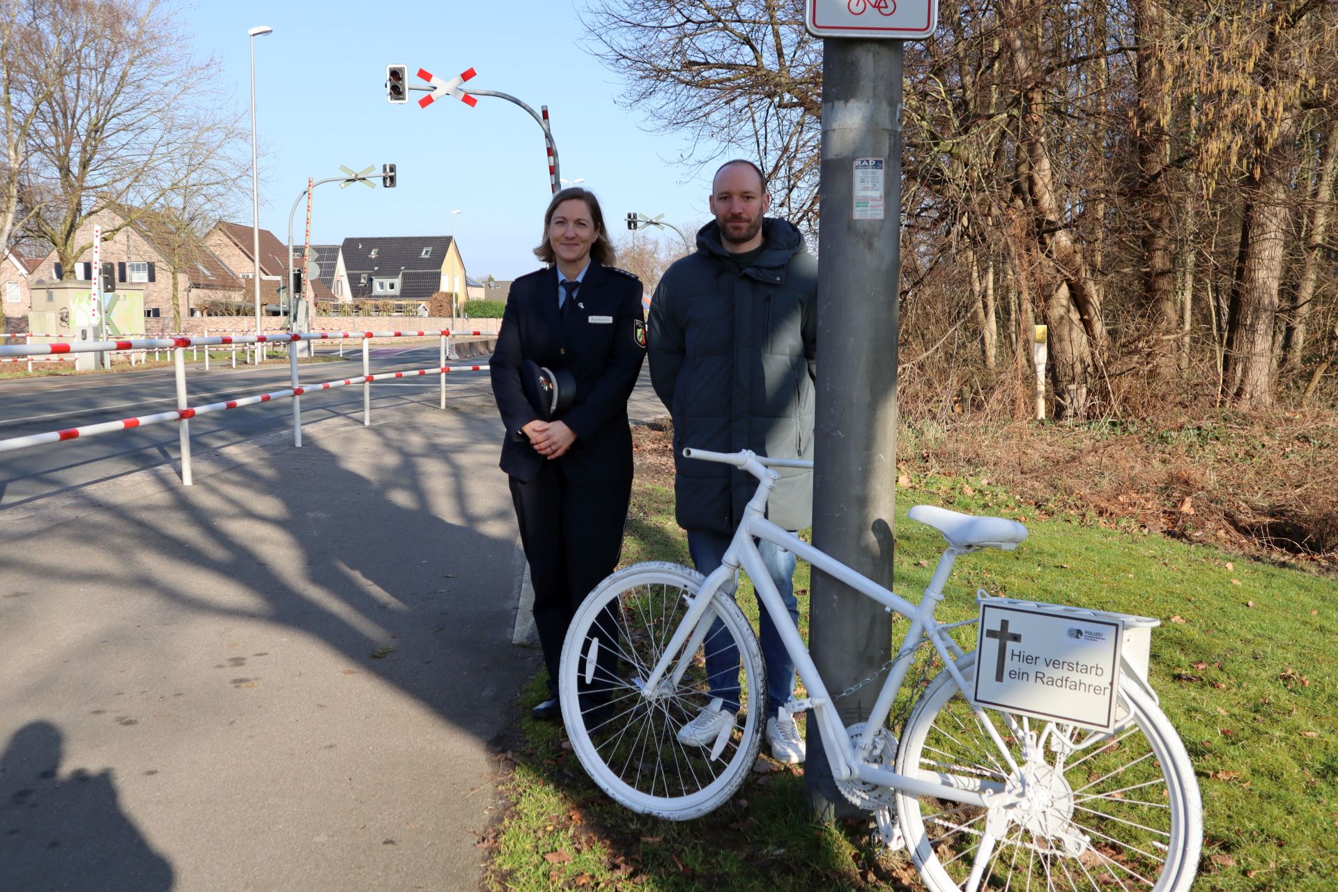 Polizeihauptkommissarin Heike Kormann und Jan Bakenecker-Serné von der Stadt Gronau stehen vor dem Mahnrad an der Gronauer Straße