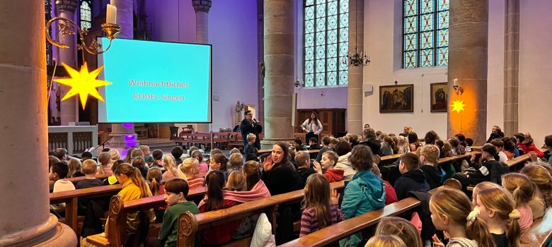 Weihnachtliches Rodel - Singen in Epe Kinder sitzen in der St. Agatha Kirche in Epe und nehmen am Rodelsingen teil.