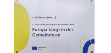 Schild mit der Aufschrift "Stadt Gronau (Westf.) ist Partner der EU-Institutionen im Netzwerk Europa fängt in der Gemeinde an". Schild mit der Aufschrift "Stadt Gronau (Westf.) ist Partner der EU-Institutionen im Netzwerk Europa fängt in der Gemeinde an".